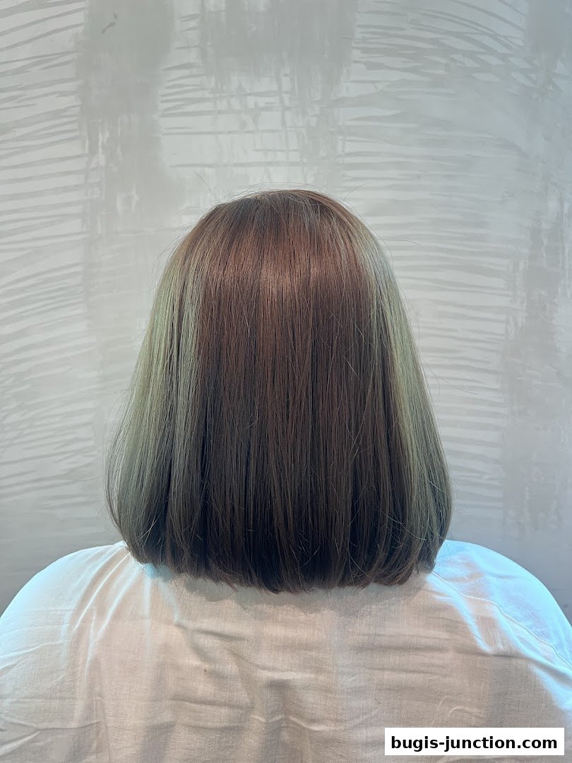 A person's back with a freshly cut bob hairstyle in a salon.