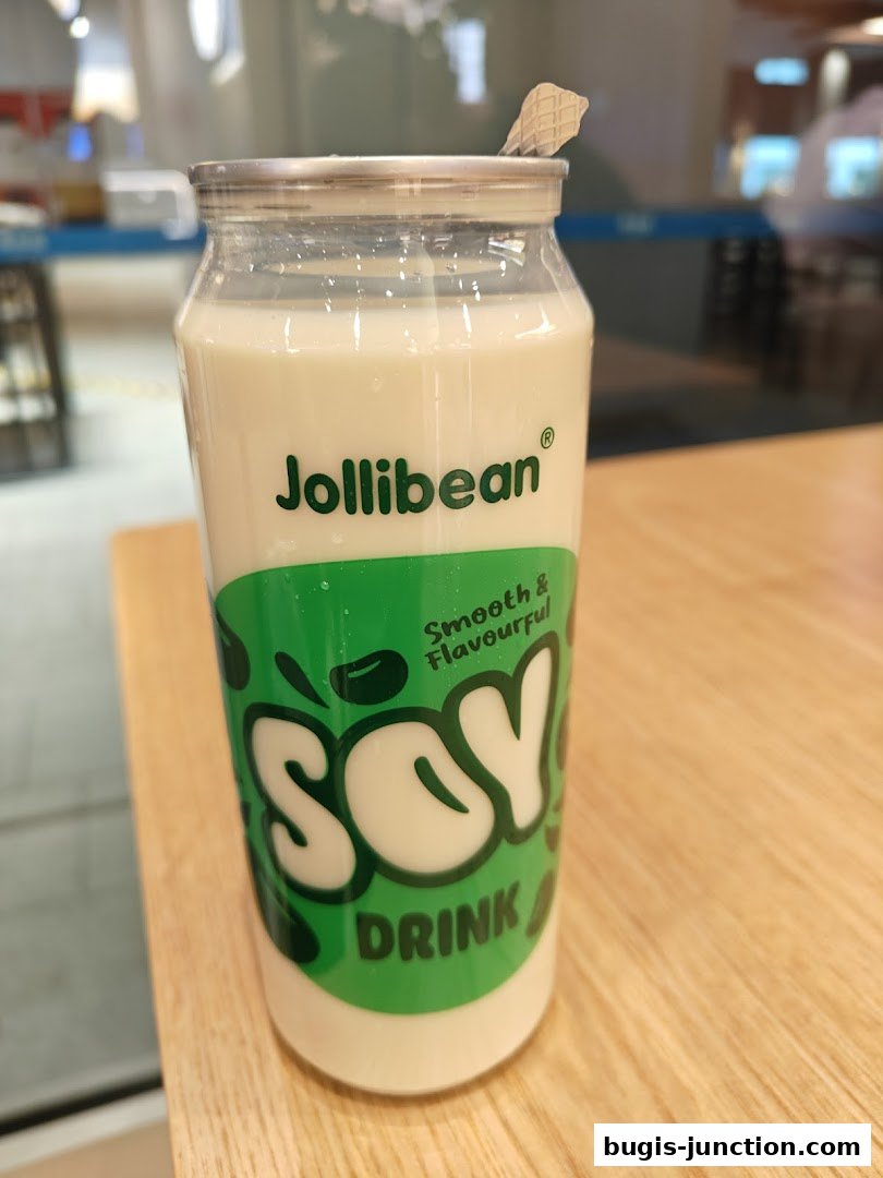 A bottle of Jollibean Soy Drink with a straw on a wooden table.
