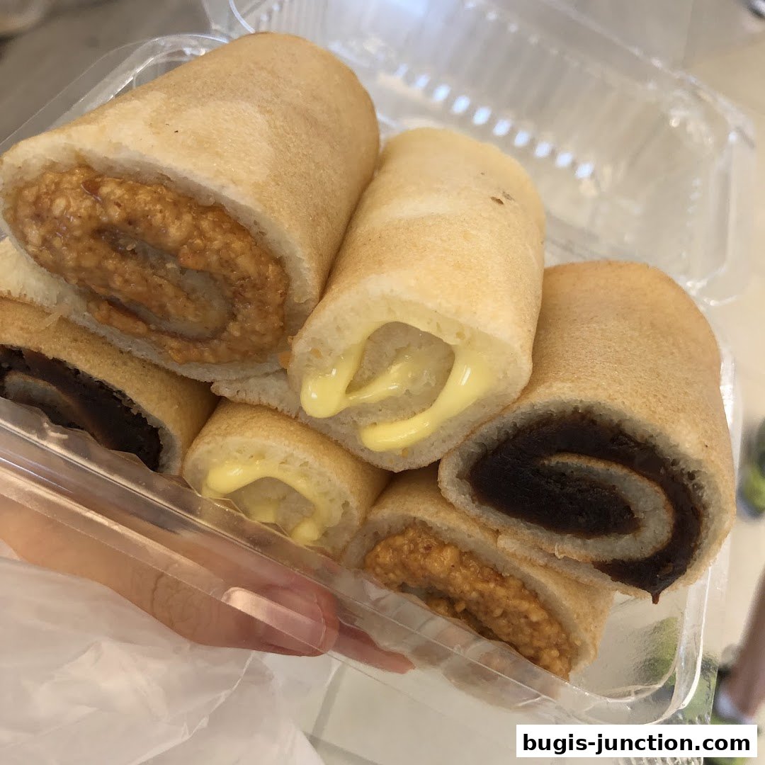 A clear plastic container filled with several rolled crepes with various fillings.