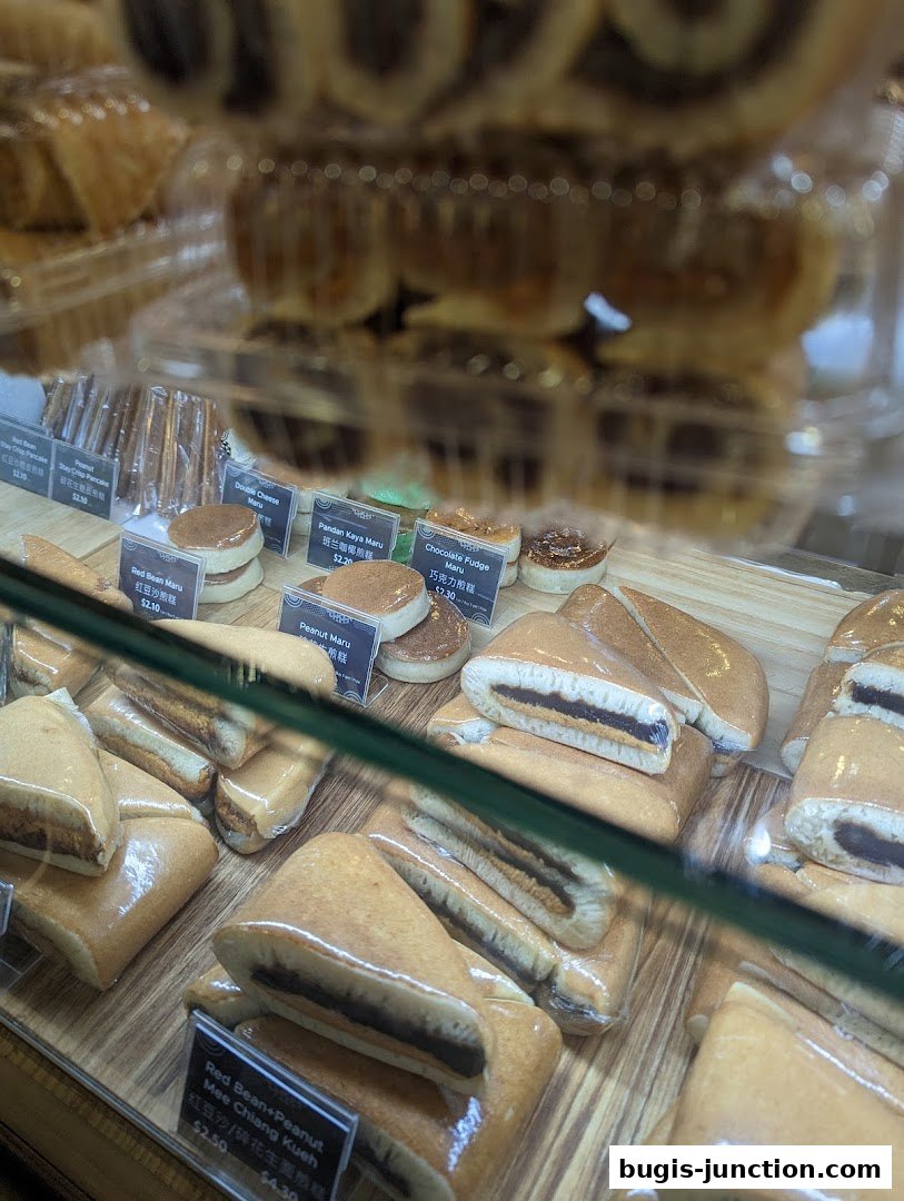 A display case filled with various sweet pastries and snacks, including pancakes and filled buns.