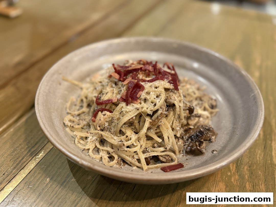 A close-up shot of a delicious pasta dish with mushrooms and bacon on a rustic wooden table.