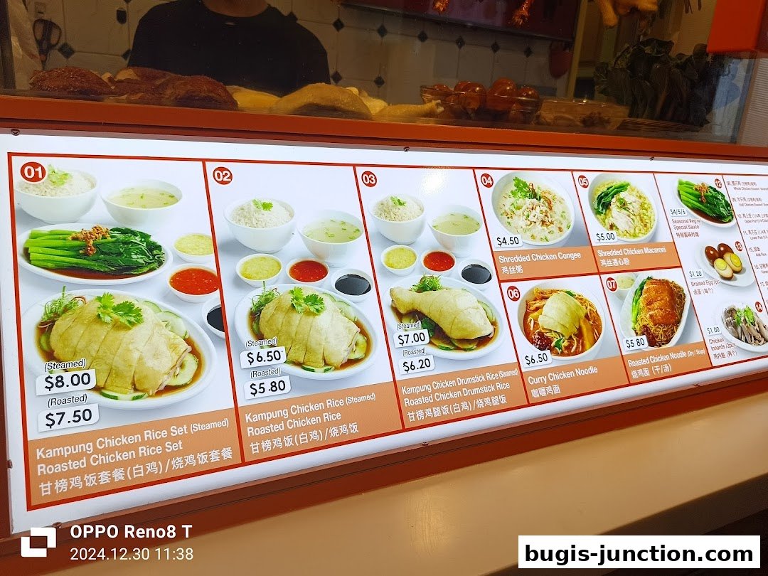 A brightly lit menu board displaying various chicken rice and noodle dishes with prices.