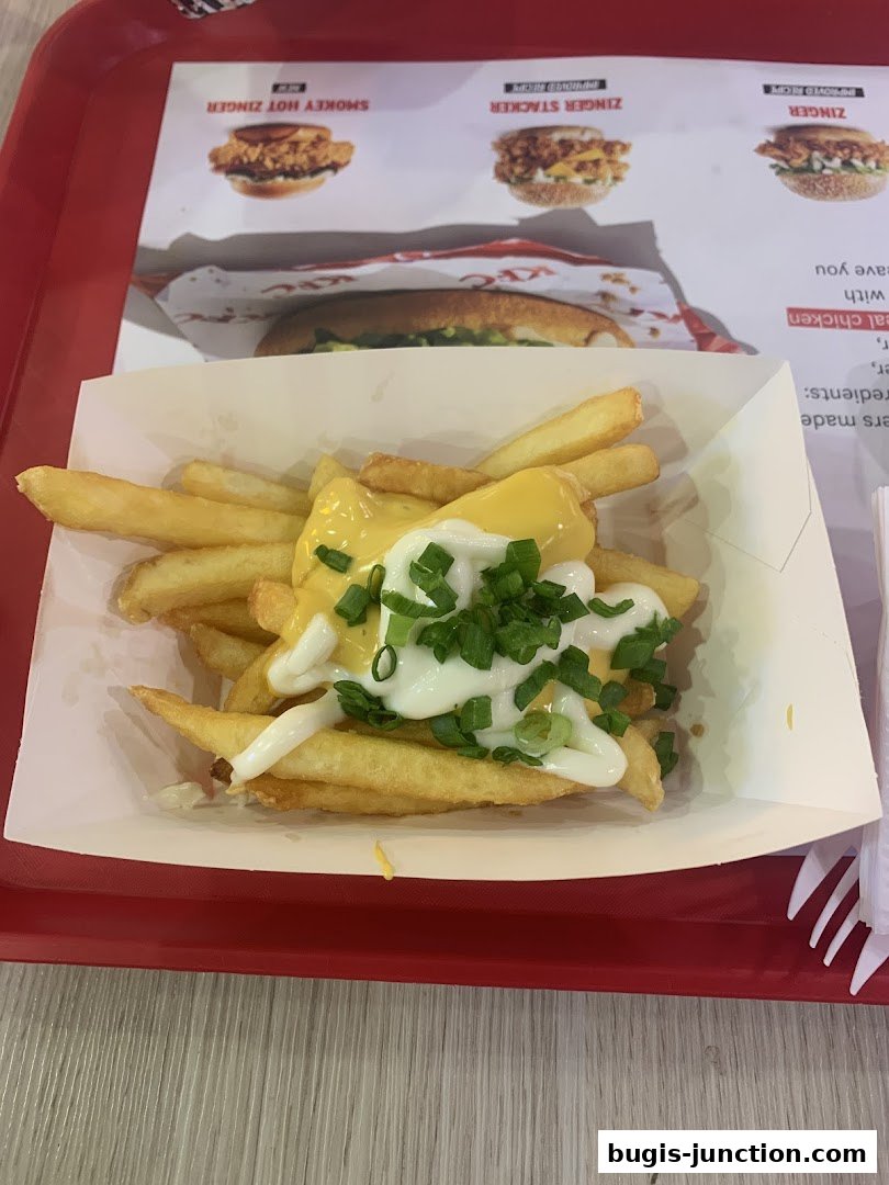 KFC fries topped with cheese sauce and chopped green onions on a red tray.