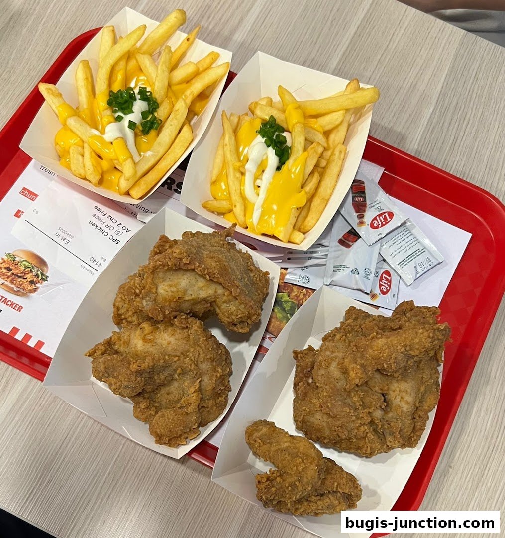 A red tray filled with KFC fried chicken, cheese fries, and condiments.