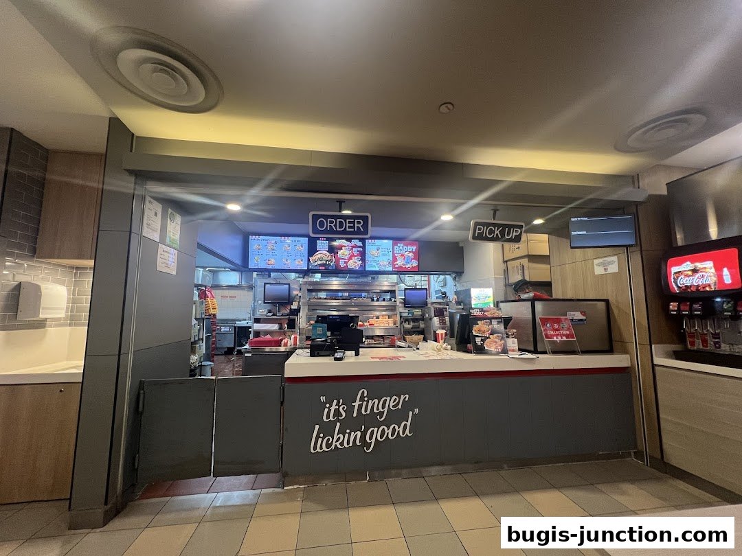 Interior view of a KFC restaurant counter with order and pick-up signs.