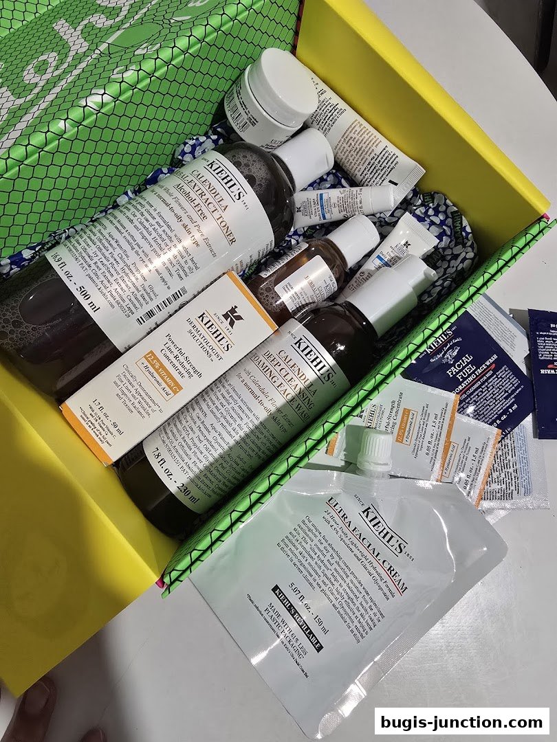 A bright yellow box filled with various Kiehl's skincare products, including toners, creams, and sample packets.