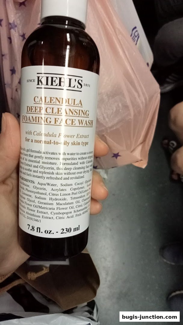 A hand holds a bottle of Kiehl's Calendula Deep Cleansing Foaming Face Wash.