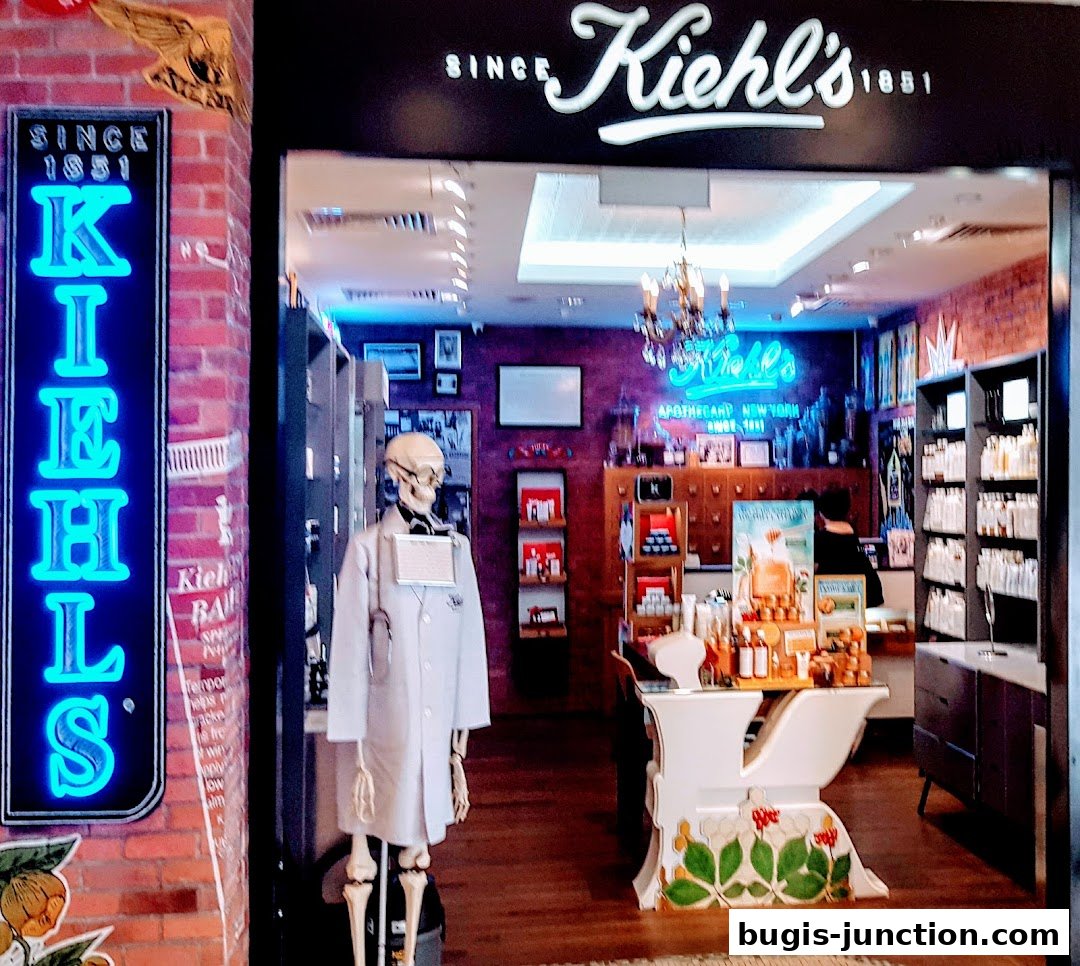 The entrance of Kiehl's Bugis Junction shop, featuring a neon sign and a skeleton mannequin.