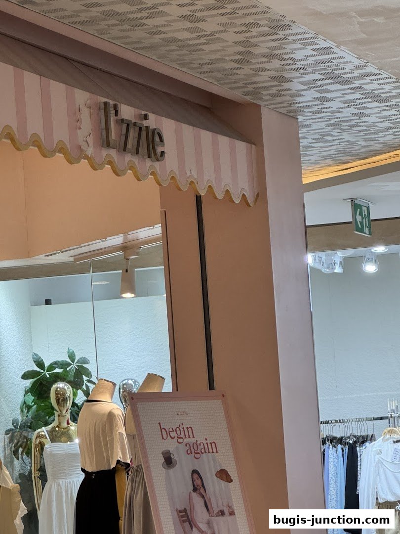 The storefront of 'Lzzie' with mannequins and a promotional poster.