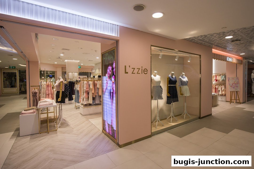 The L'zzie shop features a pastel pink facade with a well-lit interior displaying clothing on racks and mannequins.