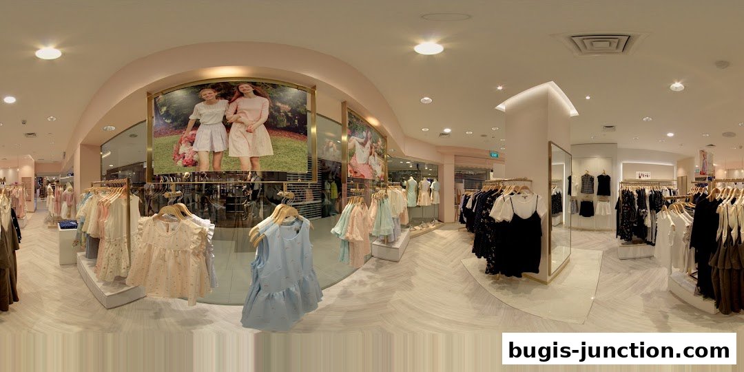 Interior view of a clothing store with racks of women's apparel and large promotional images.
