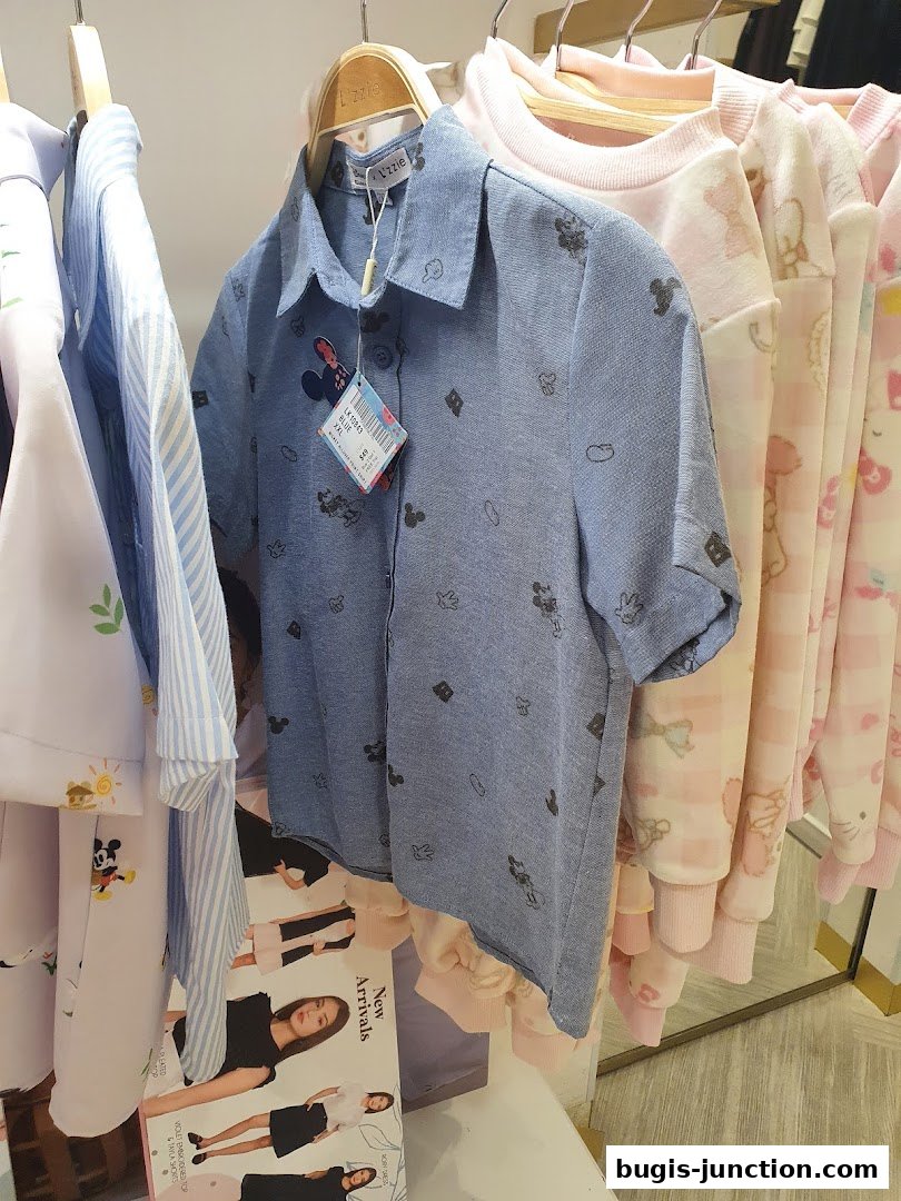 A selection of casual clothing with Disney character prints hanging on a rack.