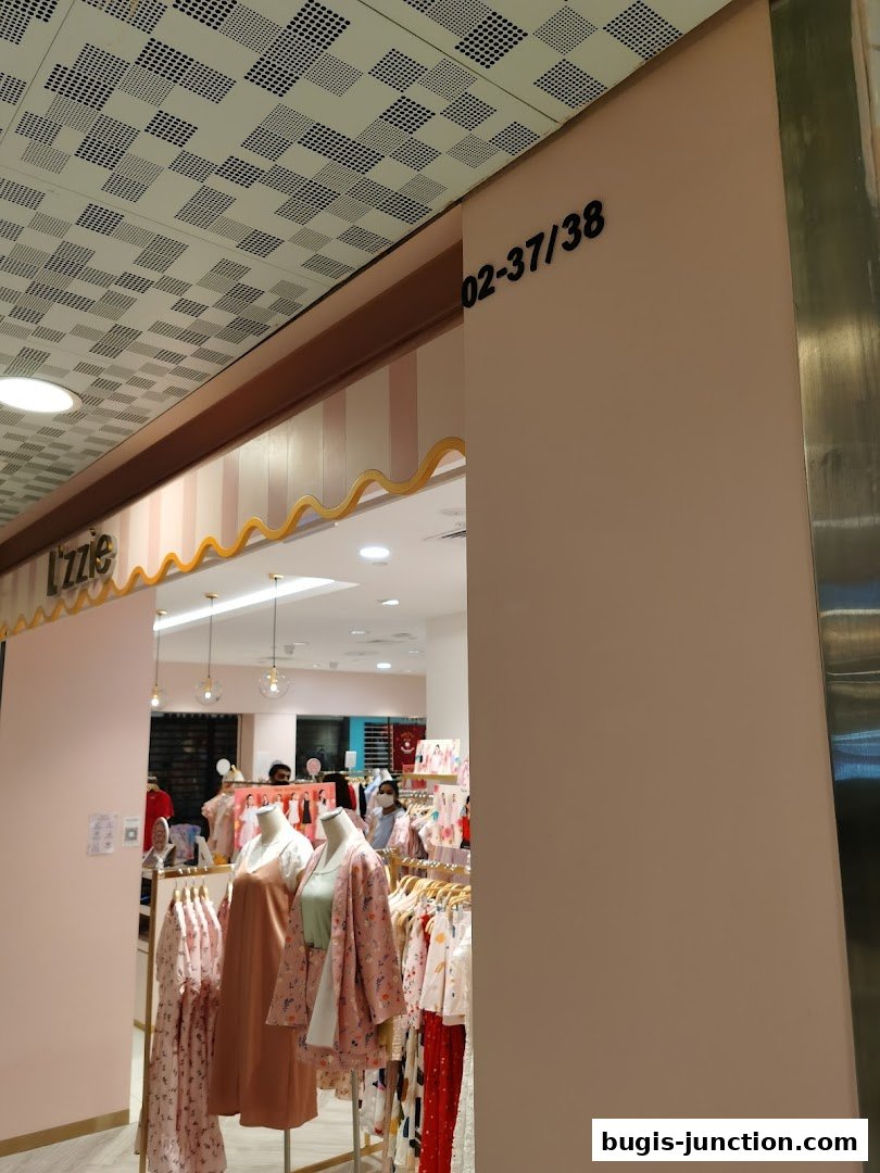 The entrance to Lzzie shop, showcasing clothing on mannequins and racks.
