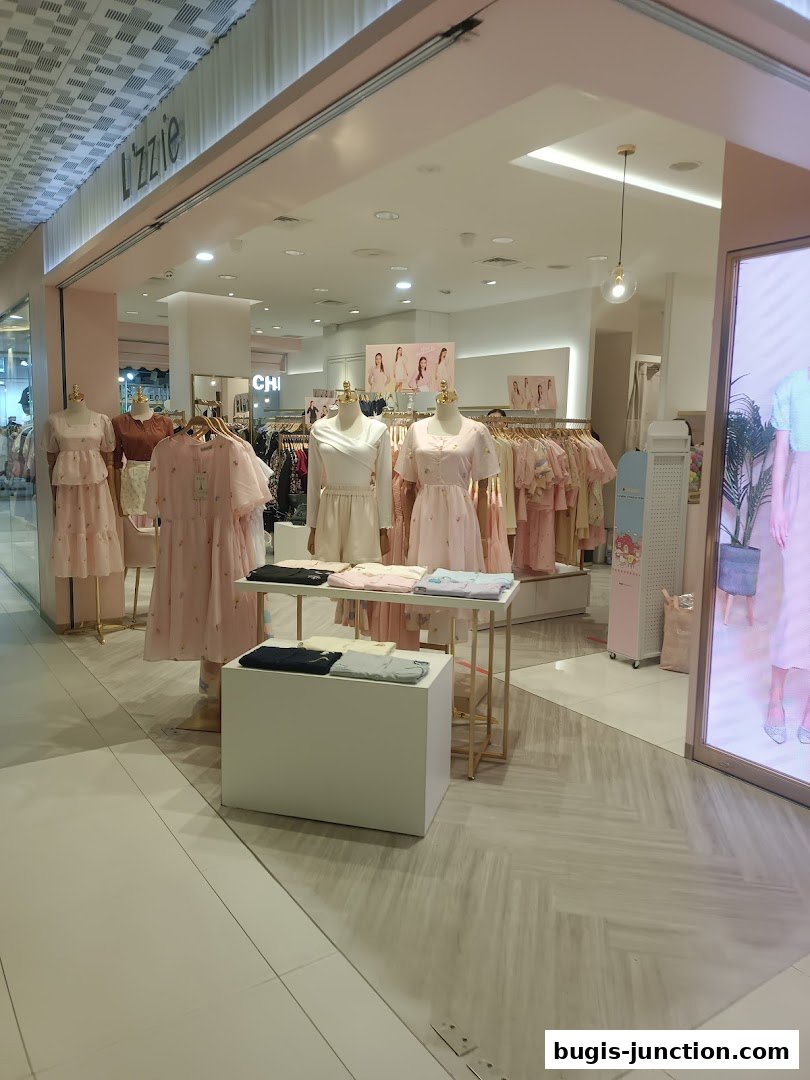 The entrance of a clothing store named Lzzie, showcasing dresses and apparel on mannequins and racks.