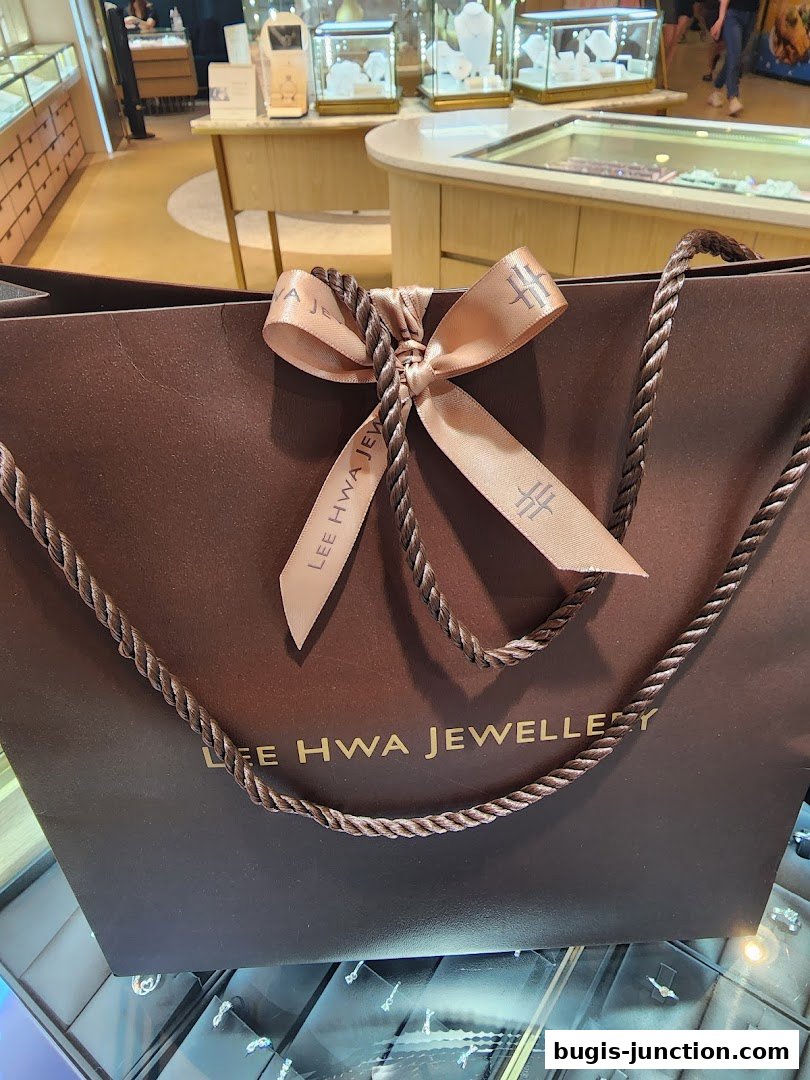 A brown shopping bag from Lee Hwa Jewellery with a ribbon tied in a bow.