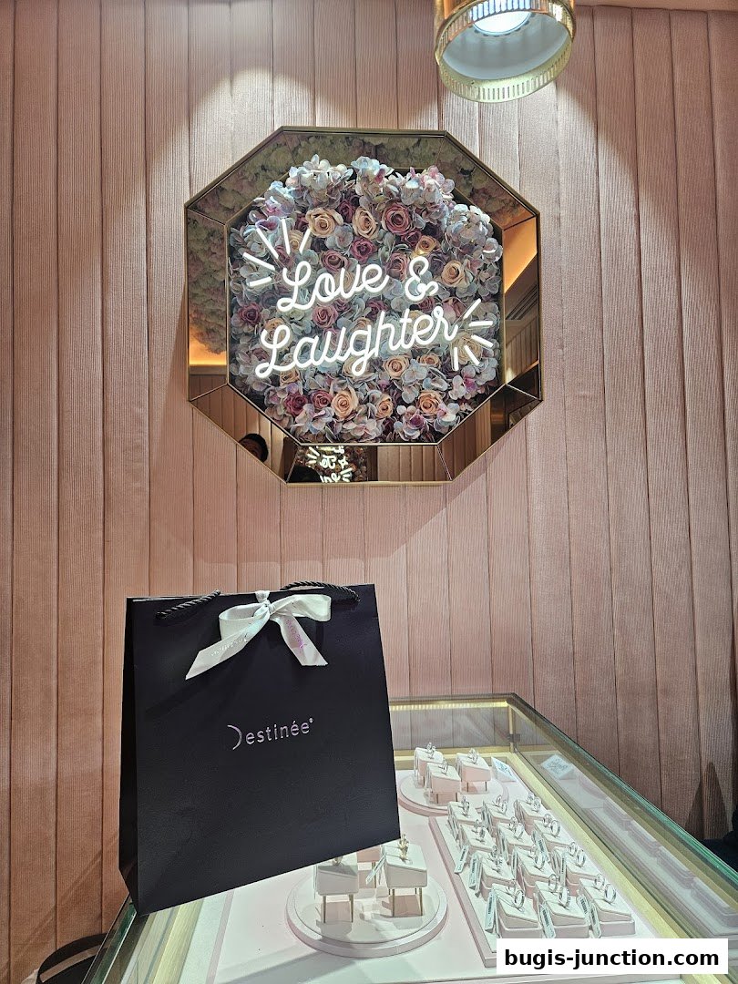 A jewelry display with a shopping bag and a floral mirror with neon text.