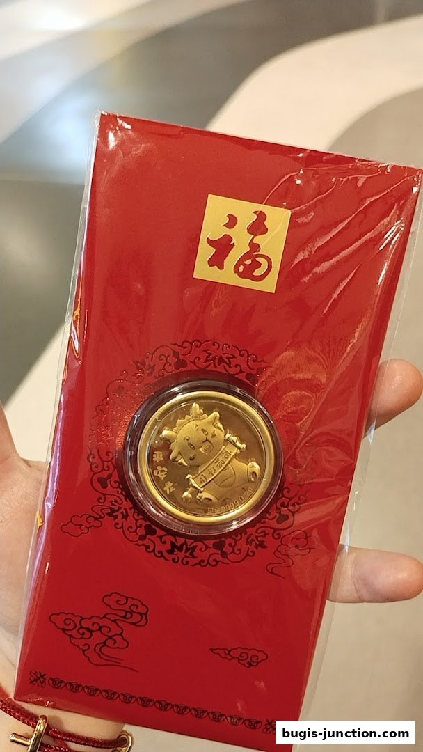 A hand holds a red packet with a gold coin featuring a cartoon bull and Chinese characters.