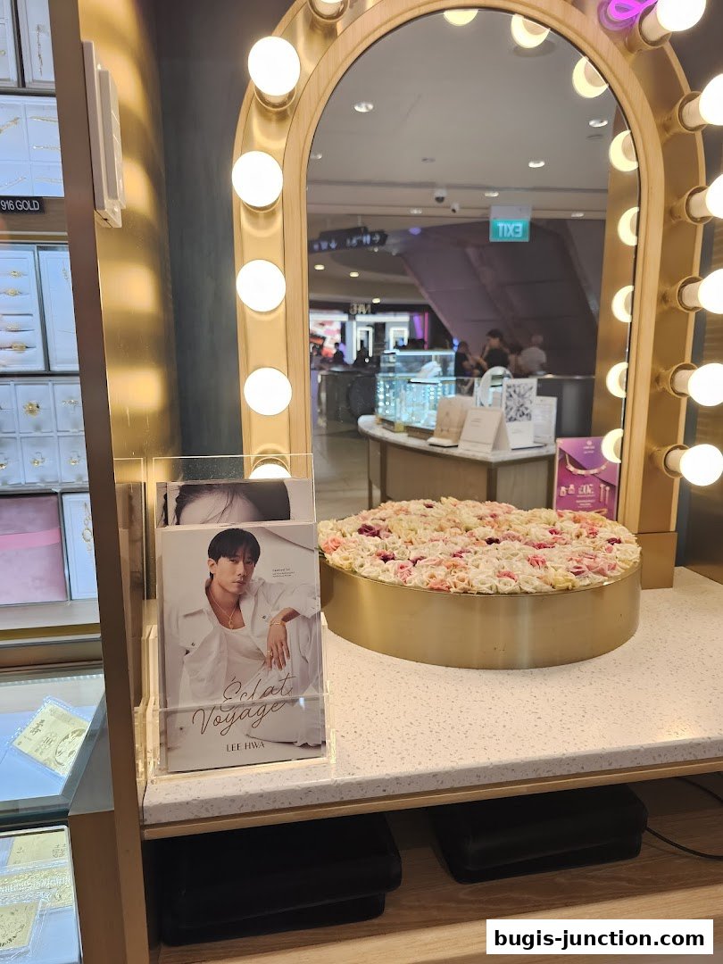 A display counter with a mirror, floral arrangement, and promotional material for Lee Hwa Jewellery.