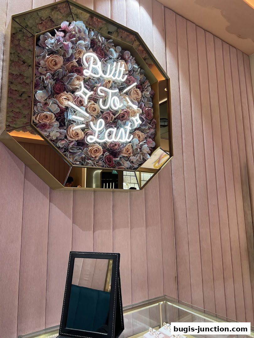 A neon sign saying 'Built To Last' is displayed on a floral arrangement in a jewelry store.