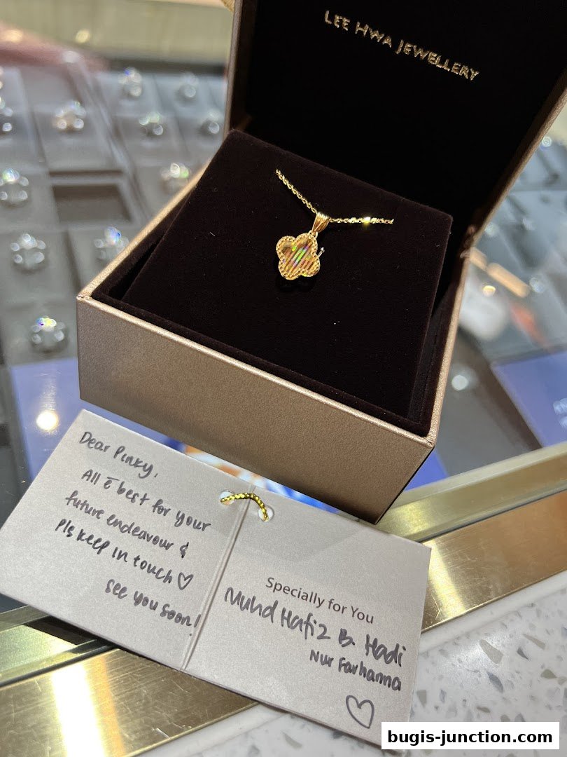 A gold pendant necklace in a jewelry box with a personalized note.