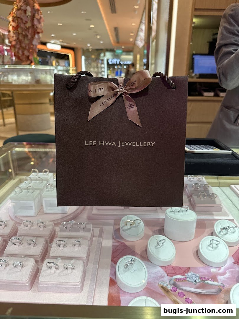 A Lee Hwa Jewellery shopping bag sits in front of a display of elegant rings.