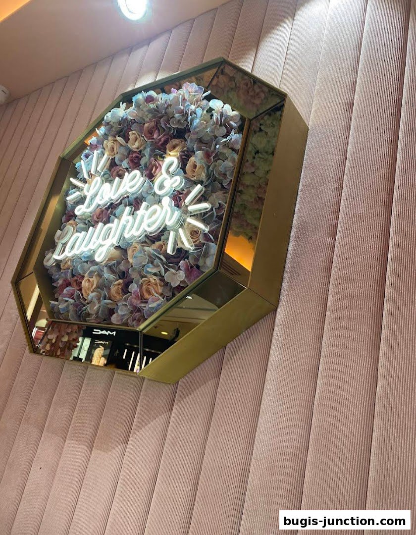 A decorative wall piece with flowers and a neon sign that says 'Love & Laughter'.