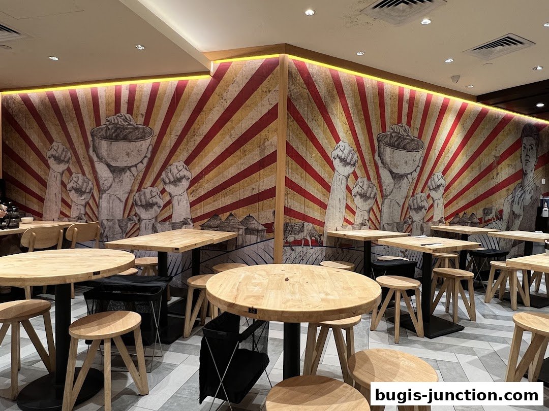Interior of LeNu Chef Wais Noodle Bar with unique mural and wooden tables and stools.