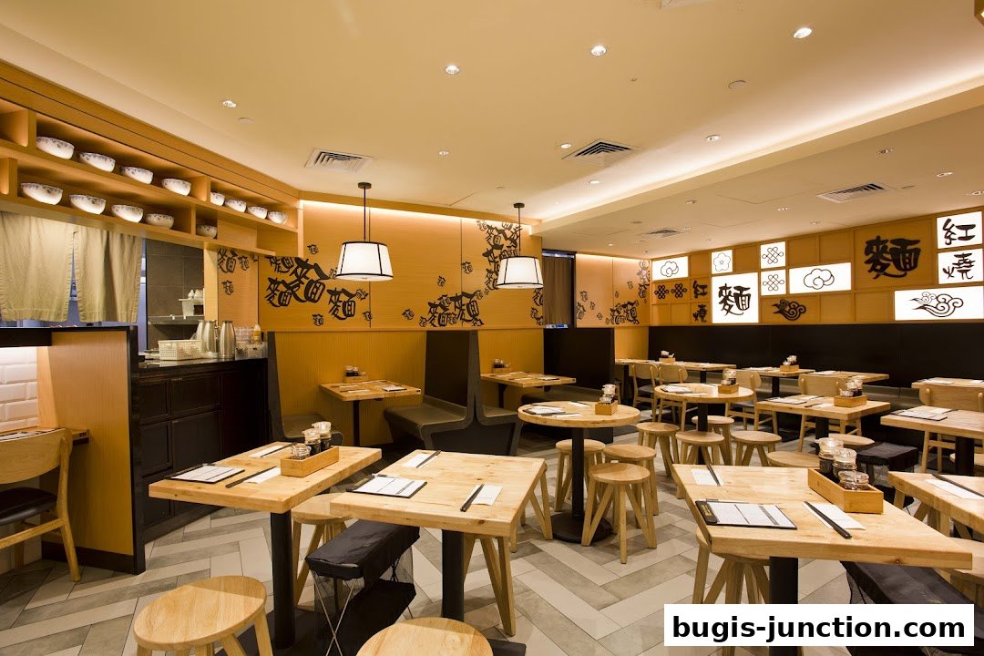 Interior of a modern noodle bar with wooden tables, chairs, and decorative wall art.