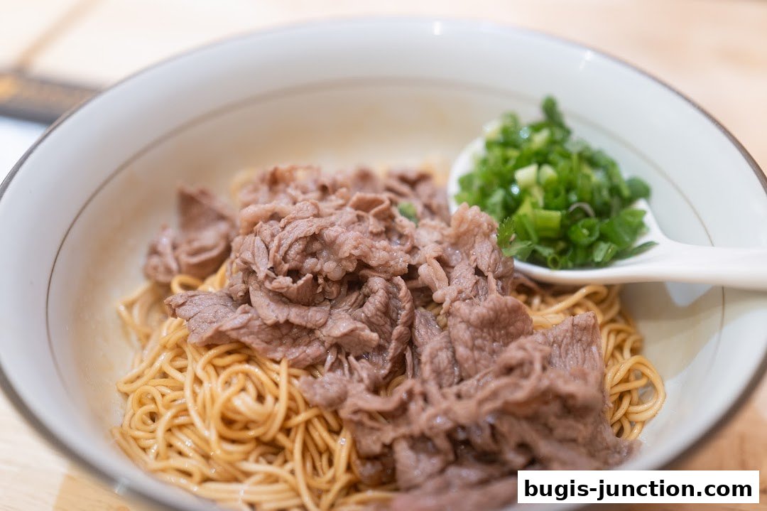 A close-up shot of a bowl of noodles topped with thinly sliced beef and chopped scallions.