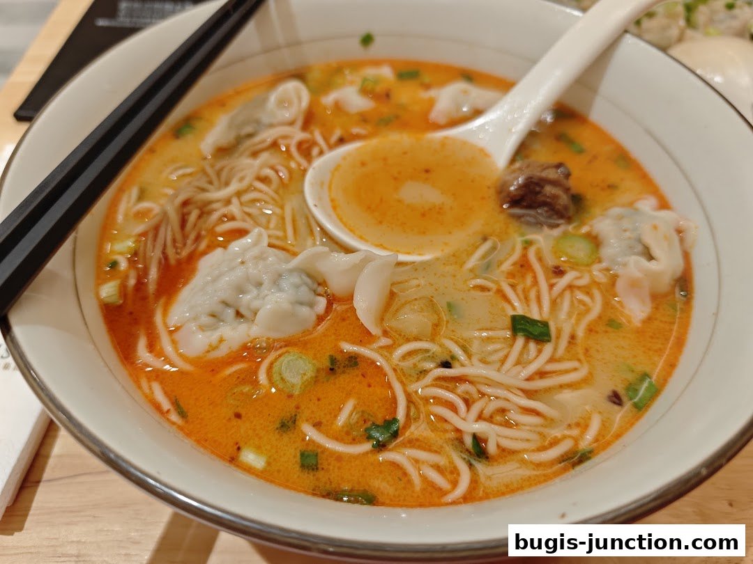A close-up shot of a steaming bowl of wonton noodle soup with chopsticks.
