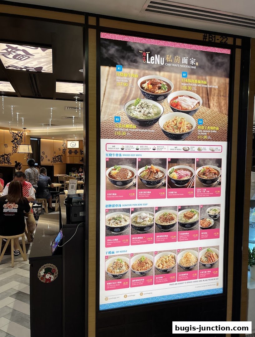 A digital menu board displaying various noodle dishes with prices at LeNu Chef Wai's Noodle Bar.