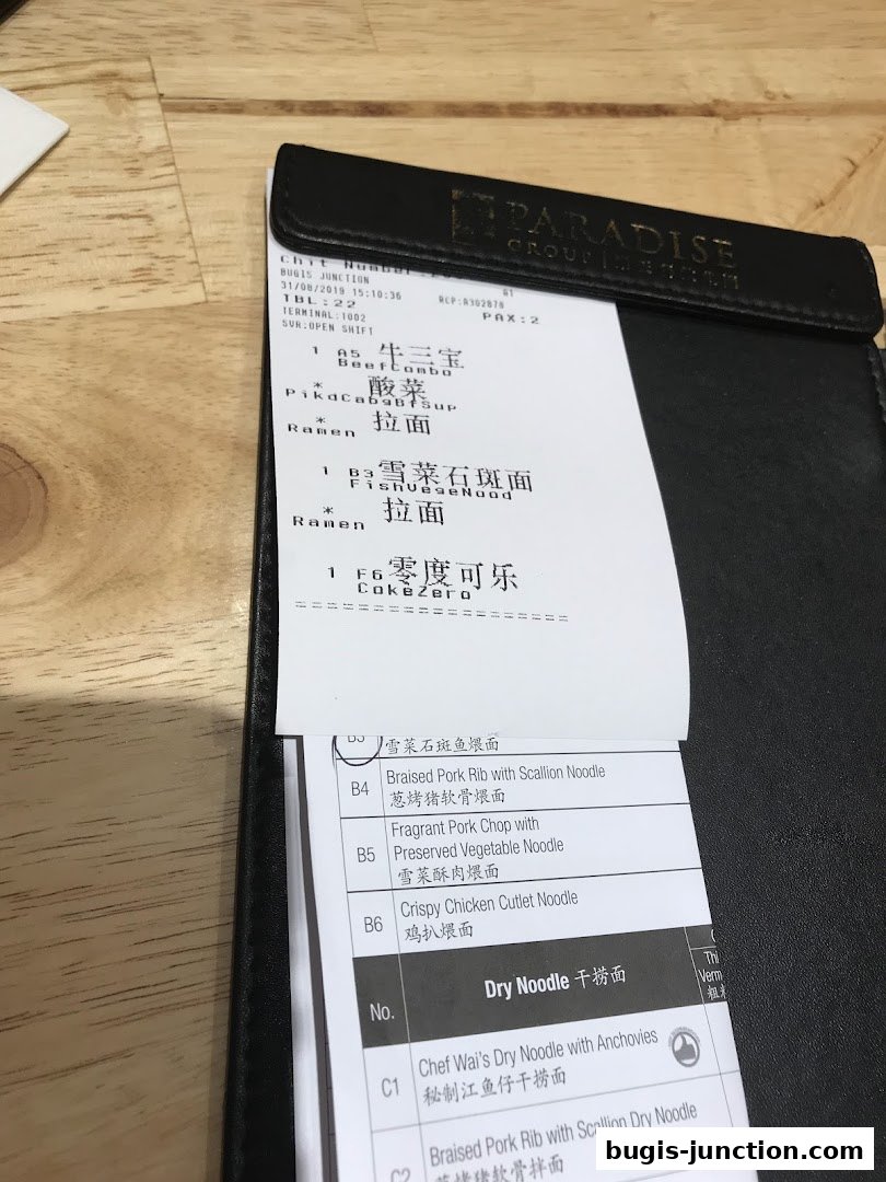 A close-up view of a restaurant receipt showing various noodle dishes and drinks.