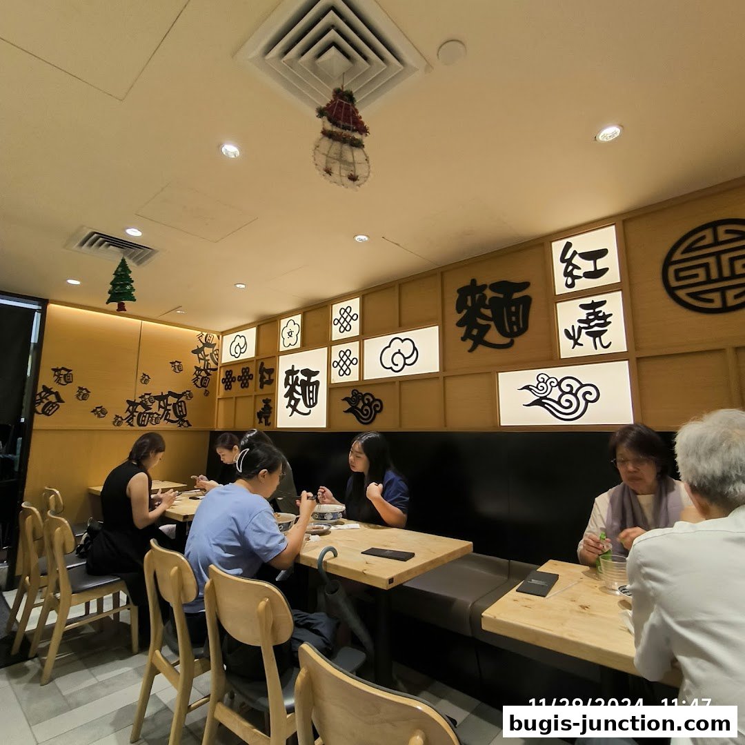 Diners enjoy meals at tables inside LeNu Chef Wais Noodle Bar, decorated with Chinese calligraphy.