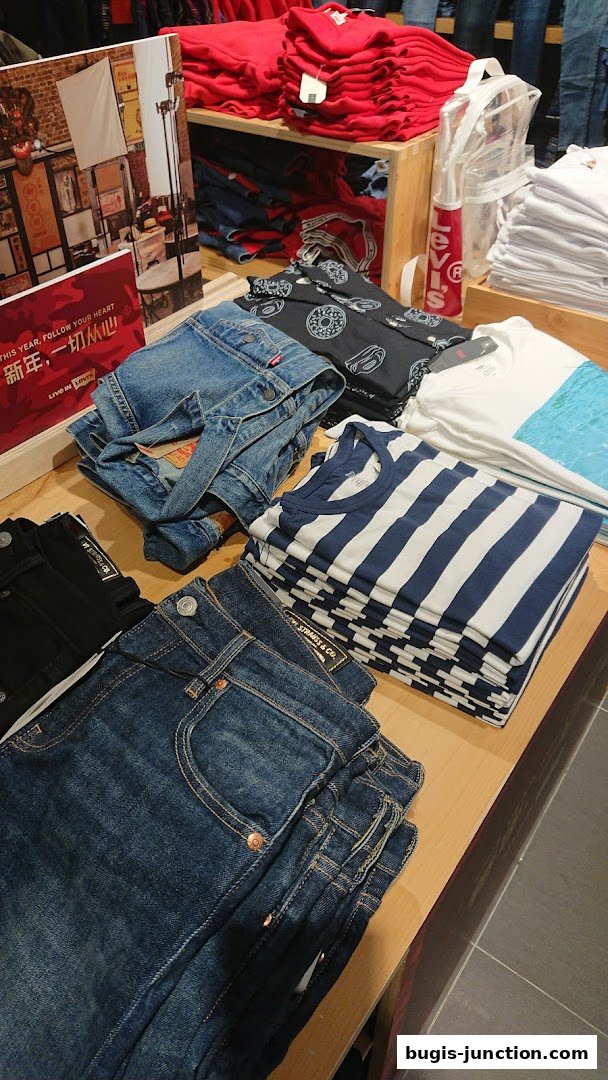 Neatly folded Levi's jeans and t-shirts displayed on a wooden counter.