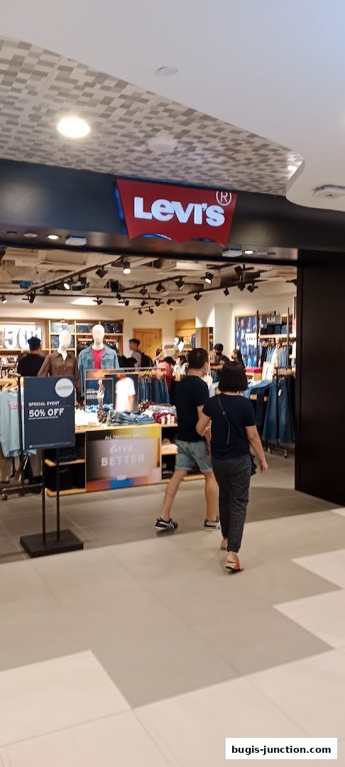 The entrance of a Levi's store with a "50% OFF" sign and mannequins displaying clothing.