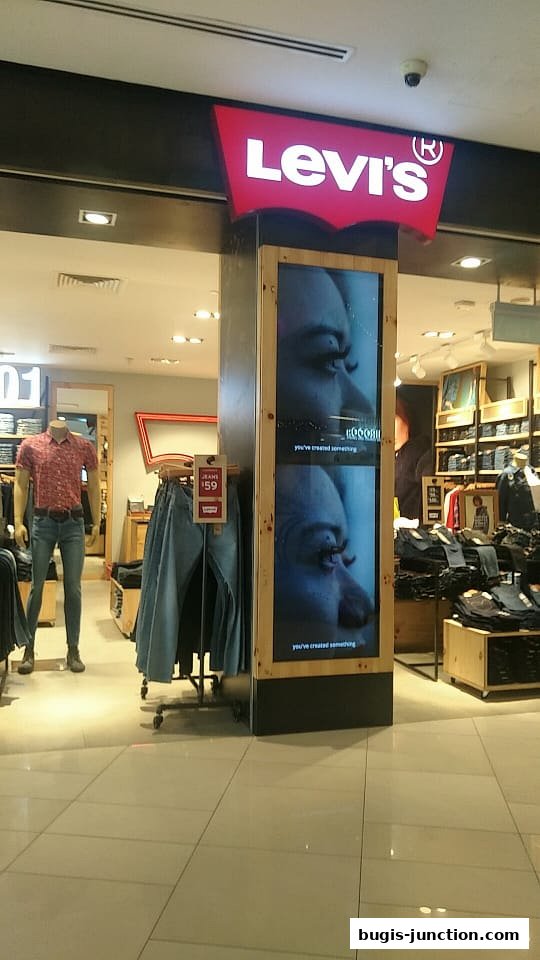 The entrance of a Levi's store with a mannequin and displayed jeans.