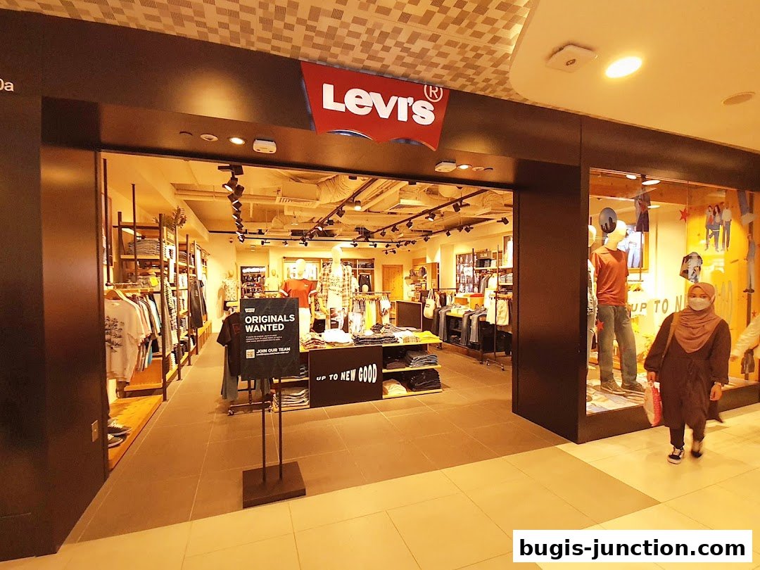 The entrance of a Levi's store with clothing displays and mannequins, and a customer walking by.