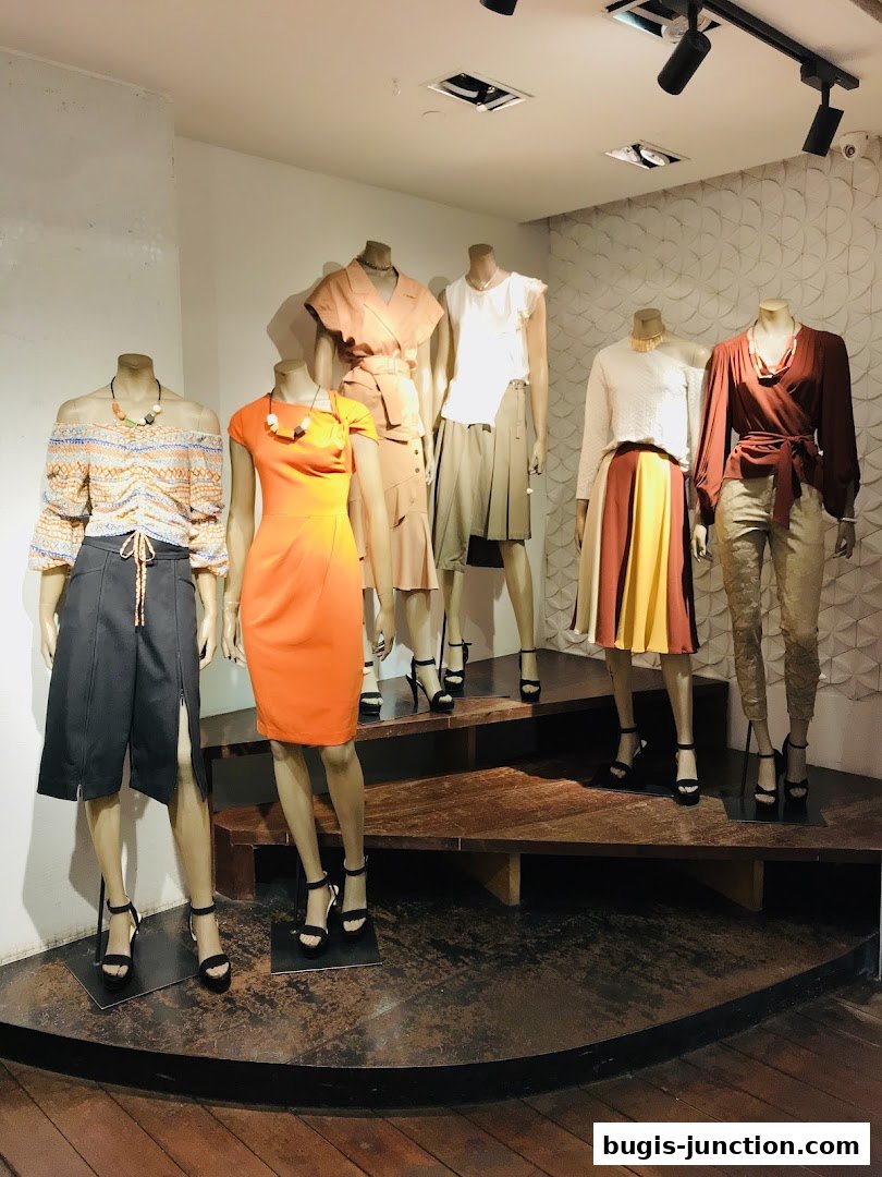 Mannequins display stylish outfits in a well-lit retail store window.