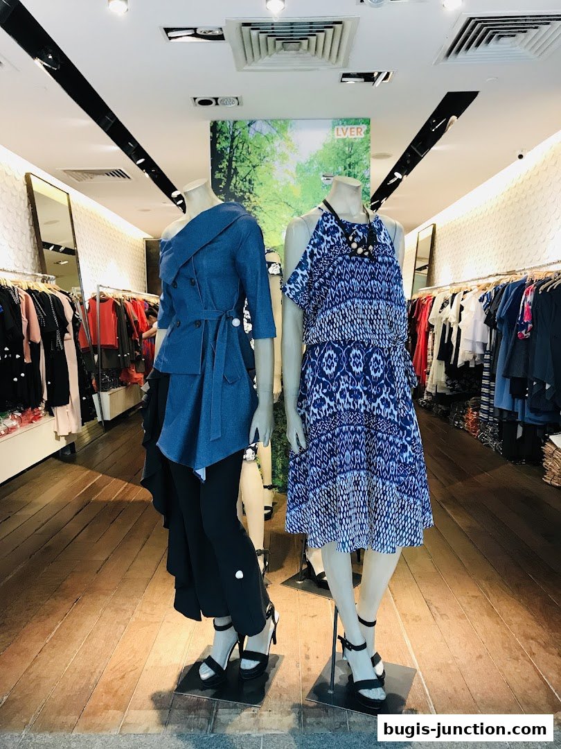 Two mannequins display stylish outfits inside a clothing store.