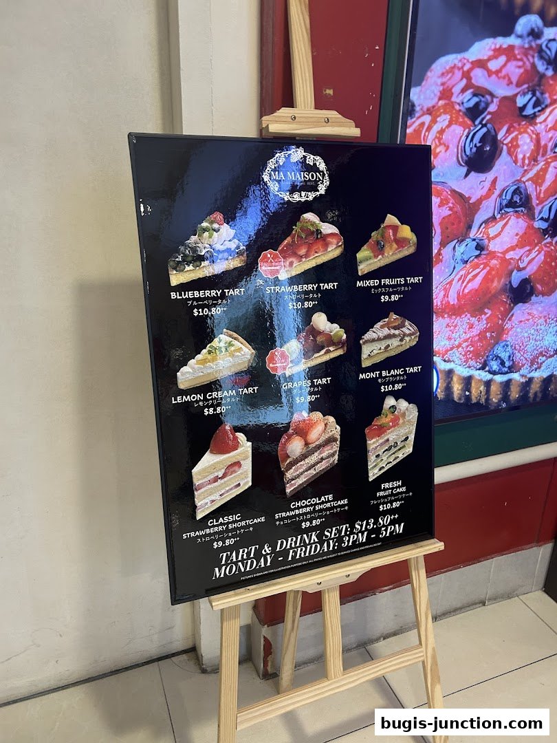 A menu board displaying various tarts and cakes from MA MAISON.