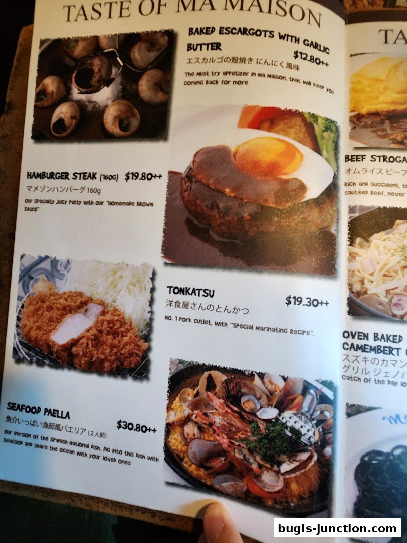 A menu from MA MAISON featuring various dishes like escargots, hamburger steak, tonkatsu, and seafood paella.