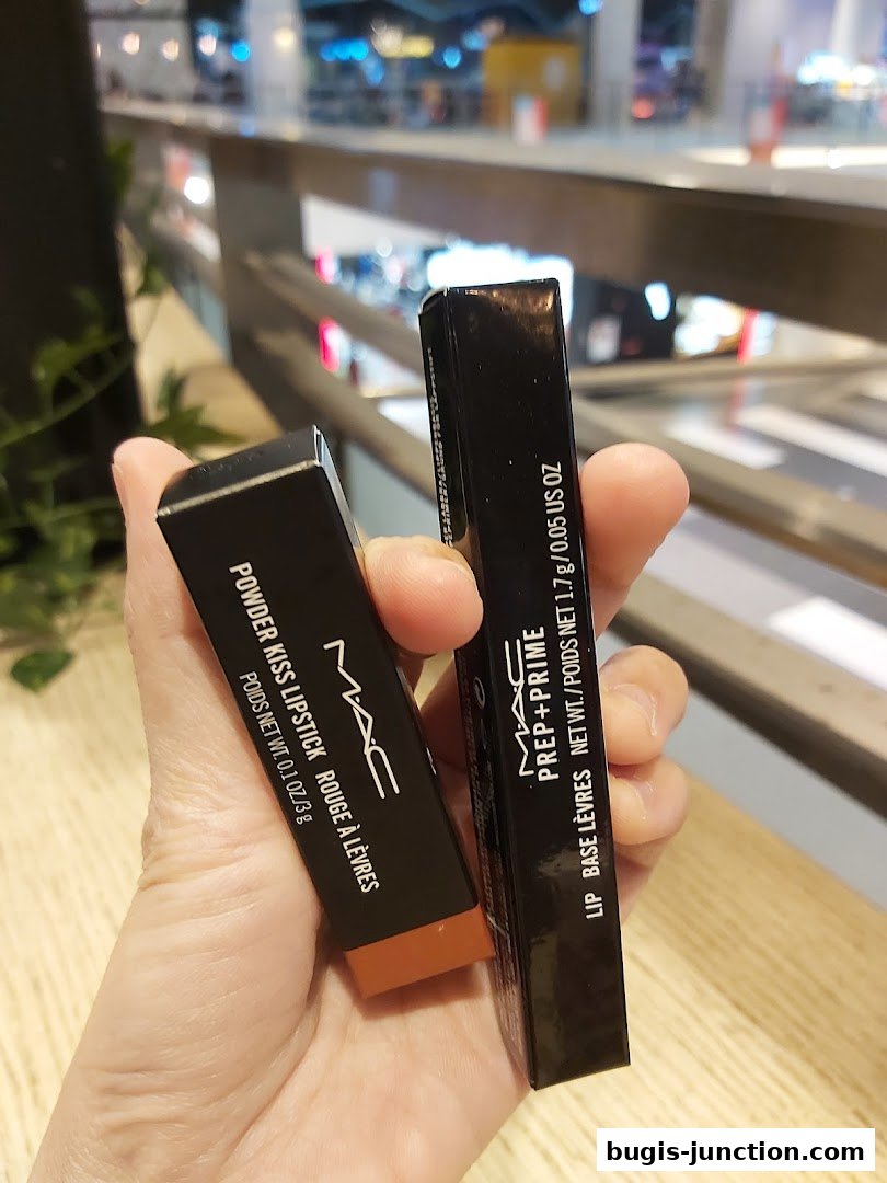 A hand holds MAC Cosmetics Powder Kiss Lipstick and Prep + Prime Lip.