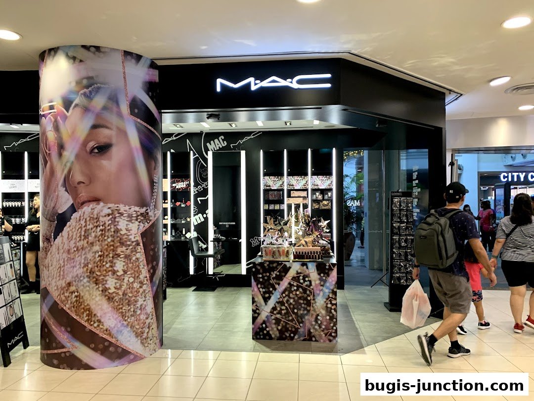 The MAC Cosmetics store entrance with a large graphic of a woman and displays of makeup.