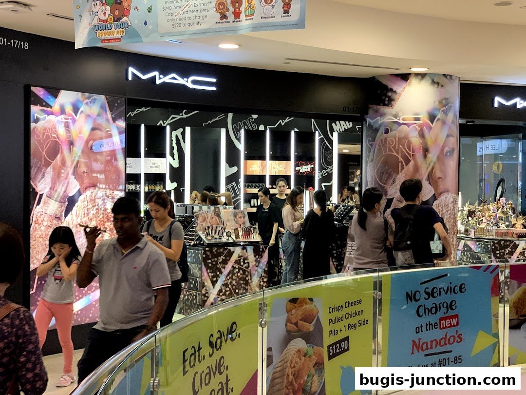 People browsing at a MAC Cosmetics store with promotional displays and makeup products.