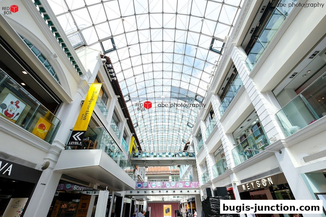 Interior view of a modern shopping mall with a glass ceiling and multiple levels of shops.
