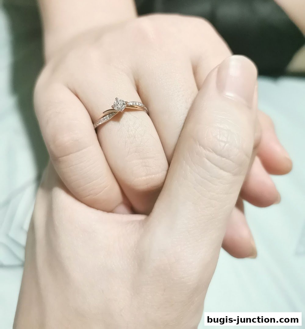 A close-up shot of two hands gently holding each other, with a diamond ring on one finger.