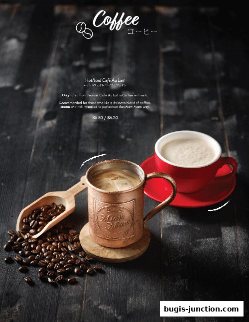 A close-up of a coffee drink with coffee beans and a scoop on a dark wooden surface.