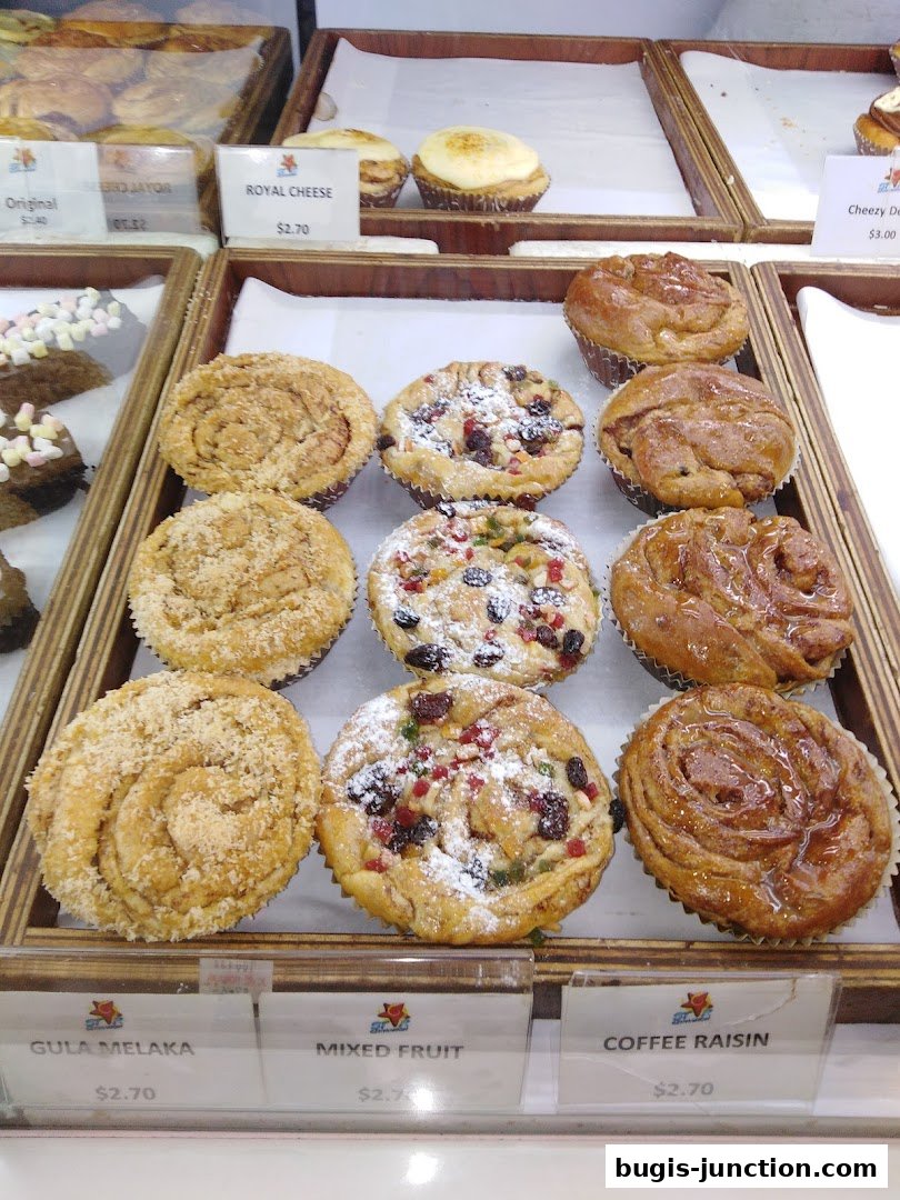 A display of freshly baked pastries including Gula Melaka, Mixed Fruit, and Coffee Raisin buns.