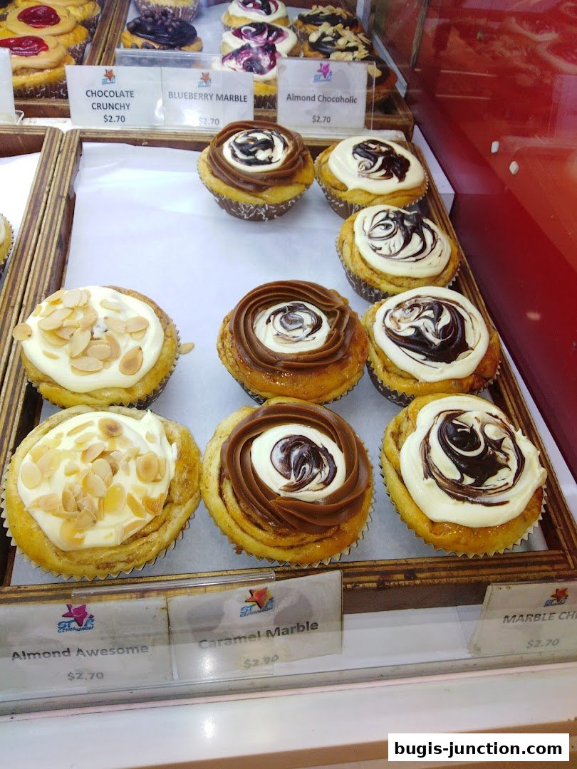 A display of various cupcakes and pastries with different toppings and flavors.