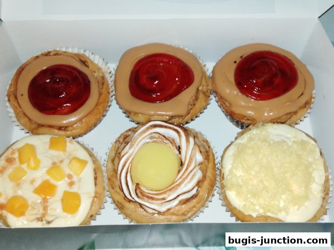 A box of six assorted pastries with various toppings including fruit and cream.